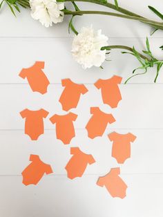 an arrangement of cut out pieces of paper with flowers on the table next to it