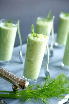 four glasses filled with green smoothie and garnished with dill