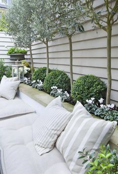 a white couch sitting on top of a wooden bench next to a lush green tree