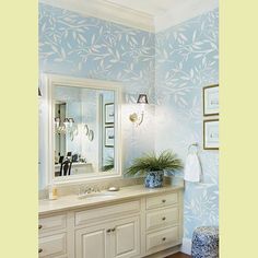 a bathroom with blue wallpaper and white cabinets