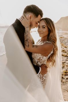 a bride and groom embracing on the beach