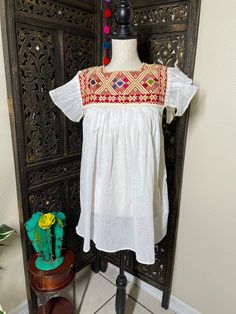 "Precious Embroidered Blouse made in Puebla, Mexico by our Mexican partners. Super light weight and fresh looking. The embroidered design is beautiful and delicate. All the work is clean, and with a professional finish and hand embroidered. You will look gorgeous for a friends night out or a summer cookout day, your call. You will Love it either way.... :) Blouse STYLE DETAIL Overview * soft cotton fabric * round-neck * hand embroidered design * short sleeves fit & sizing *21\" from underarm Festive Spring Embroidered Top With Short Sleeves, Spring Festive Embroidered Short Sleeve Top, Festive Short Sleeve Top With Embroidered Neckline, Festive Embroidered Short Sleeve Top For Spring, White Geometric Embroidered Short Sleeve Dress, White Embroidered Top With Embroidered Hem For Festival, White Short Sleeve Embroidered Dress With Geometric Pattern, White Embroidered Top With Hem Detail For Festivals, White Short Sleeve Dress With Geometric Embroidery