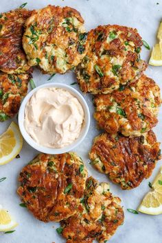 several crab cakes with lemon wedges and a small bowl of mayonnaise on the side