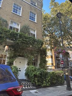 a car parked in front of a tall brick building with ivy growing on it's side