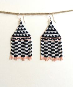 black and white beaded earrings hanging from a string on a wall with two strings