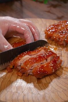 a person cutting meat with a knife on a wooden table