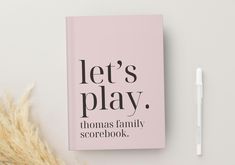 a pink book with the words let's play on it next to a pen