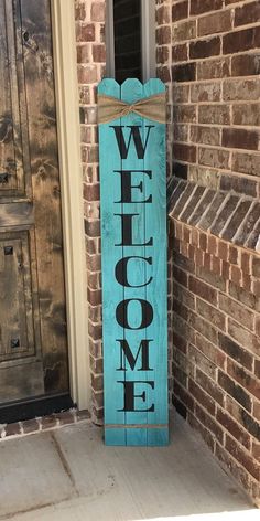 a wooden welcome sign sitting on the side of a brick wall next to a door