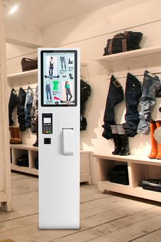 a white vending machine sitting inside of a store filled with jeans and boots on display