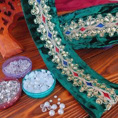 some beads are laying on a table next to a green velvet bag and other items