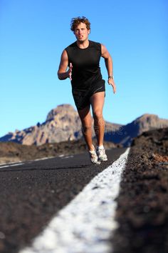 a man is running down the road with mountains in the background