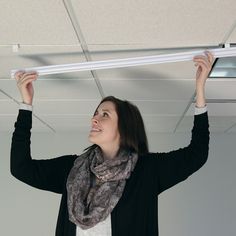 a woman is smiling while holding up a white piece of furniture above her head and wearing a scarf around her neck