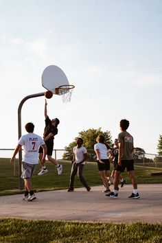 a group of young men playing basketball in a park