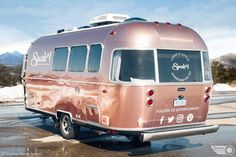 an old pink camper parked on the side of the road with mountains in the background