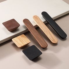 four different wooden magnets sitting next to each other on a white surface with black and brown ones