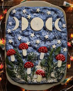 a cake decorated with mushrooms and stars on top of a wooden table covered in snow