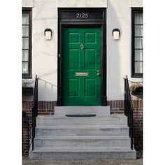 a green door on the side of a white building with steps leading up to it