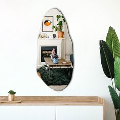 there is a mirror on the wall above a table with plants in front of it