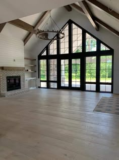 an empty room with wood floors and large windows