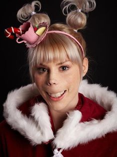 a woman with blonde hair wearing bunny ears and a red coat, smiling at the camera