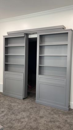 an empty room with two gray bookshelves and carpeted flooring in it