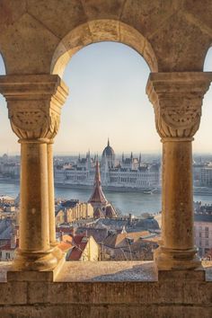 an aerial view of the city and its surrounding buildings, taken through two stone archways