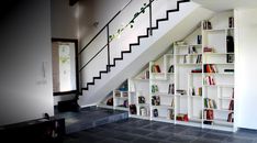 a book shelf under the stairs with books on it