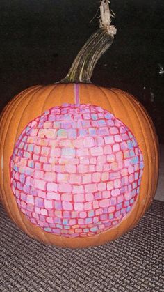 an orange pumpkin decorated with pink and blue squares