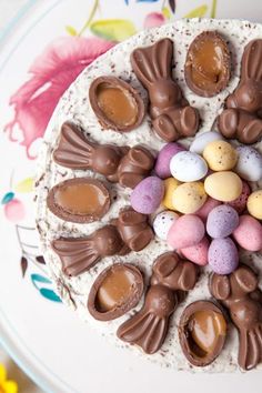 a cake decorated with chocolate eggs and candy candies on a plate next to flowers