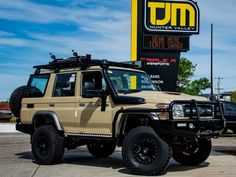 a tan four door suv parked in front of a sign