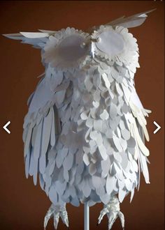 an owl made out of white paper sitting on top of a metal stand with its eyes closed