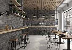 the interior of a restaurant with wooden tables and stools in front of a brick wall