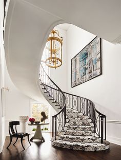 a spiral staircase in a home with white walls and wood flooring, framed artwork on the wall