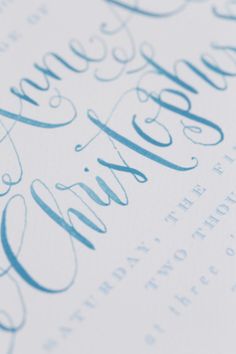 a close up view of some type of calligraphy with blue ink on white paper