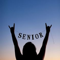 the silhouette of a woman with her hands in the air holding up a sign that says senior