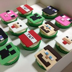 cupcakes made to look like video games are displayed on a white table with green and pink frosting