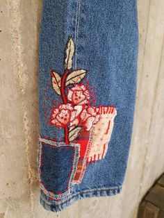 an old pair of jeans with flowers painted on them hanging from the side of a wall