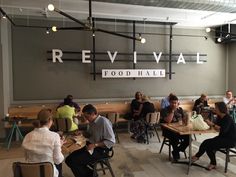 people sitting at tables in front of a sign that reads revival food hall on the wall