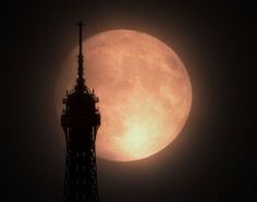 the full moon is seen behind a tower