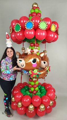 a woman standing next to a bunch of balloons with reindeers on top of it