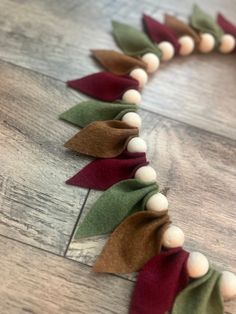 a close up of a wreath made out of felt and wood beads on a wooden floor