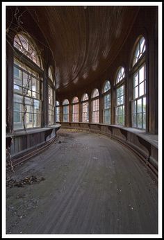 an empty room with large windows and wood flooring on the walls, in front of several arched windows