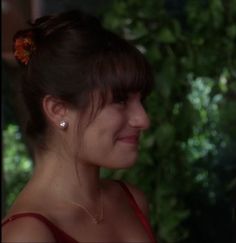 a woman with a flower in her hair looking off to the side and smiling at something