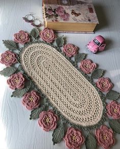 a crocheted doily is laying on a table next to a pink car