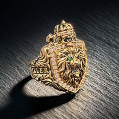 The King of Men's Gold Family Crest Rings Behold The King of Men's Gold Family Crest Ring, a majestic masterpiece that embodies power, legacy, and eternal strength. This extraordinary ring is more than just a piece of jewelry; it is a symbol of your regal heritage and indomitable spirit. Centerpiece Shield and Symbolism: At the heart of this majestic ring lies a shield adorned with a roaring lion head, symbolizing courage, nobility, and leadership. Crowning the lion is a skull, an emblem of impe Family Crest Ring, Lion Crest, Family Crest Rings, Eye Piercing, Lion Jewelry, Ancient Kingdom, Roaring Lion, Mens Gold Rings, Diamond Eyes