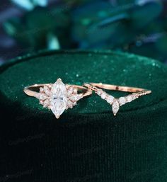 two gold rings with white diamonds on top of a green velvet hatbox, one is wearing