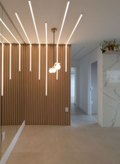 a room that has some lights hanging from it's ceiling and the walls are lined with wooden slats