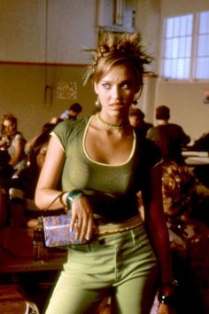 a woman standing in front of a group of people wearing green pants and crop tops