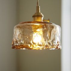 a glass light hanging from a ceiling in a room with a white wall behind it