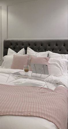 a bed with pink and white pillows on top of it next to a mirror in a room